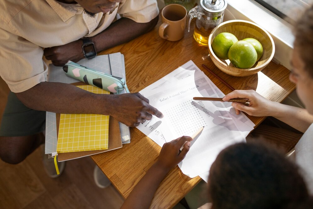 Personnes travaillant sur une grille de mots cachés à une table en bois.