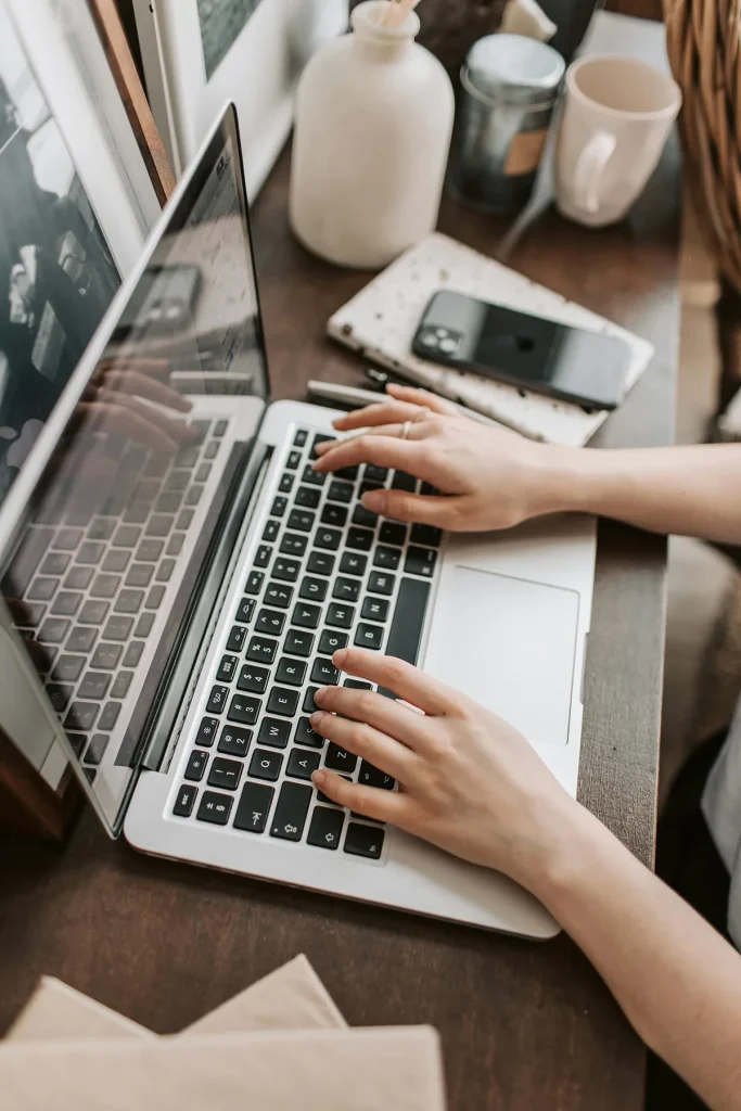 Personne tapant sur un ordinateur portable avec téléphone et tasse sur le bureau.