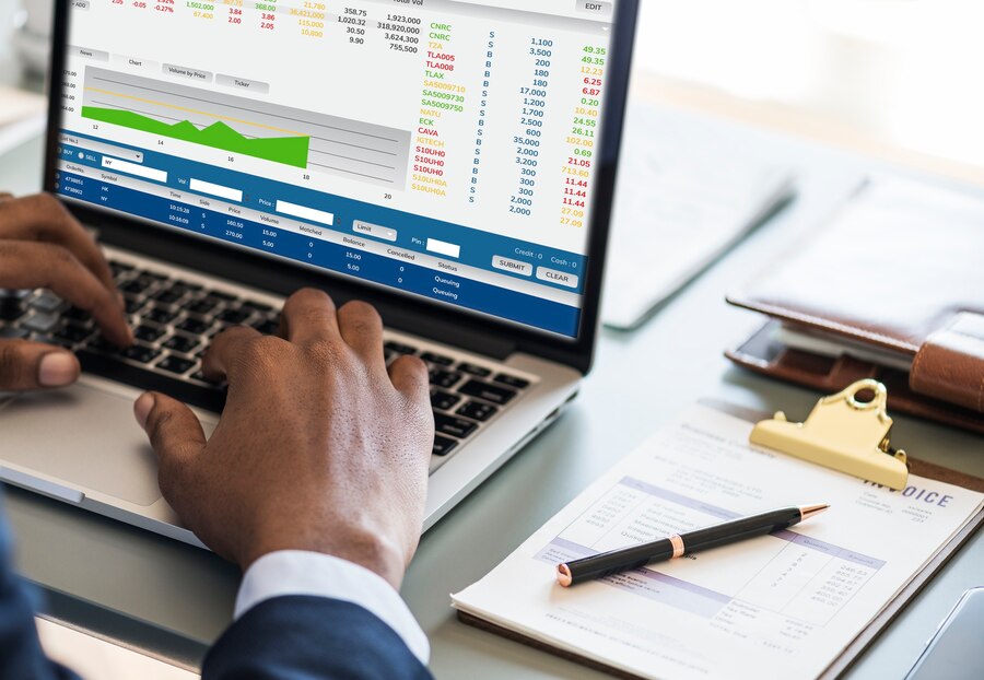 Personne utilisant un ordinateur portable avec des graphiques financiers à l'écran.